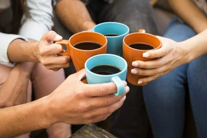 Fyra kaffekoppar som hålls av händer