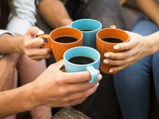 Fyra kaffekoppar som hålls av händer