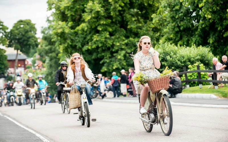 Flera personer åker gamla mopeder genom en gata
