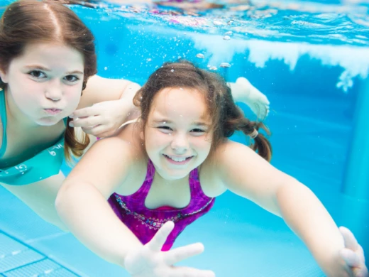 Två flickor simmar i en pool.