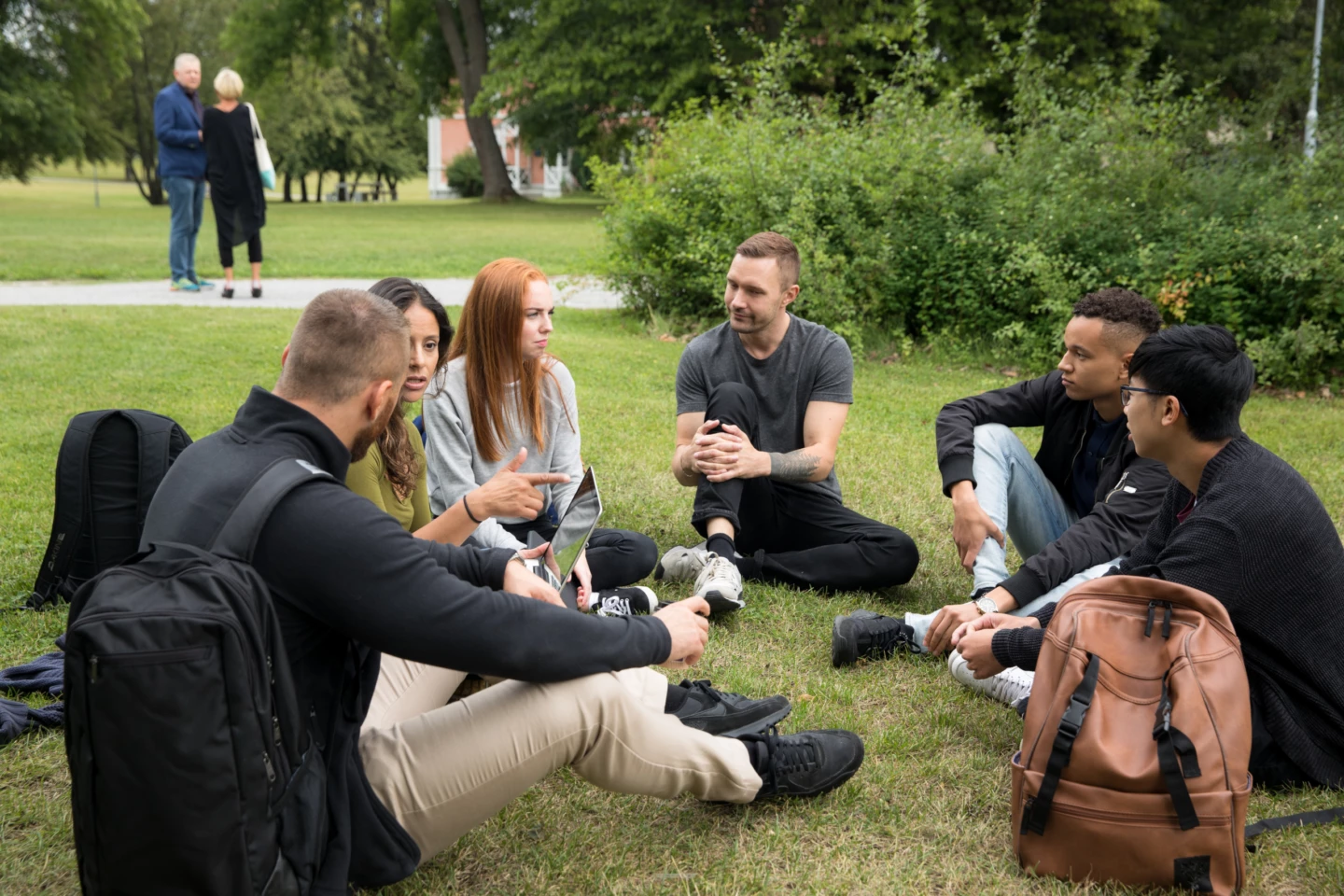 N&aring;gra ungdomar sitter i en ring p&aring; gr&auml;set utanf&ouml;r campus.