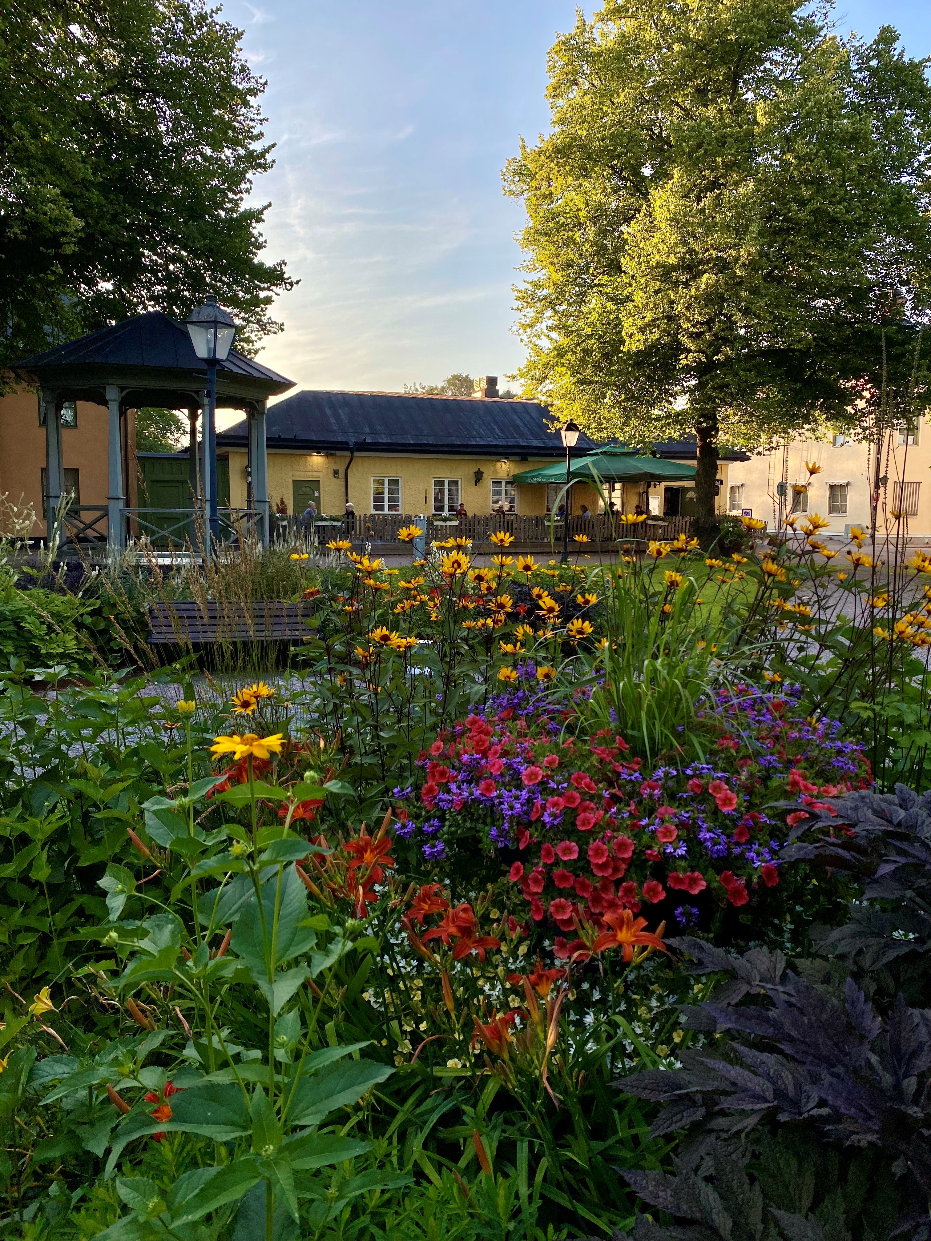 R&aring;dhustorget i S&auml;ter med f&auml;rgglada blommor i rabatterna och uteservering i bakgrunden