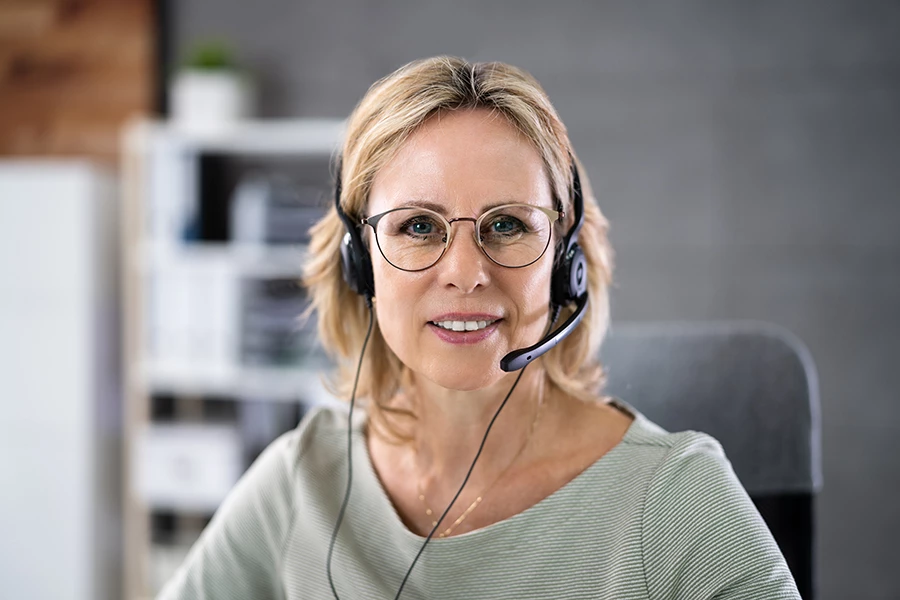En kvinna med headset sitter i kundtjänst