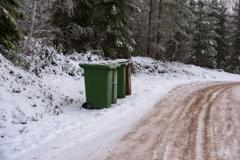 flera soptunnor som står efter en vinterväg